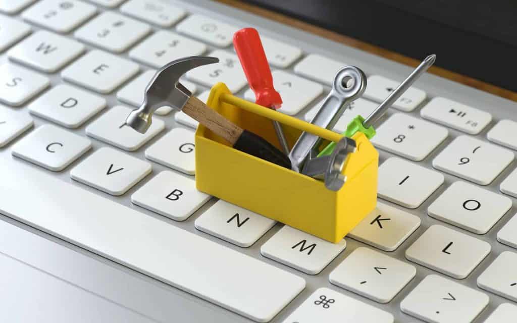 A yellow toolbox with miniature tools on a computer keyboard, representing the importance of website maintenance for small businesses.