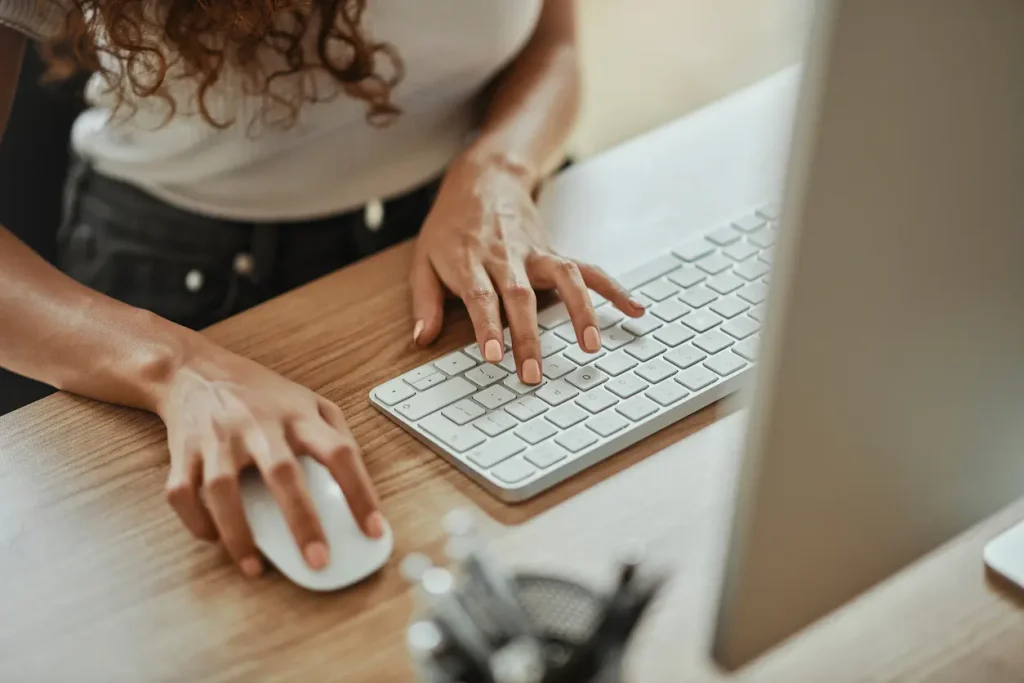 Close-up of a woman using a keyboard and mouse at a desk, symbolising local SEO efforts and digital marketing strategies for small businesses.